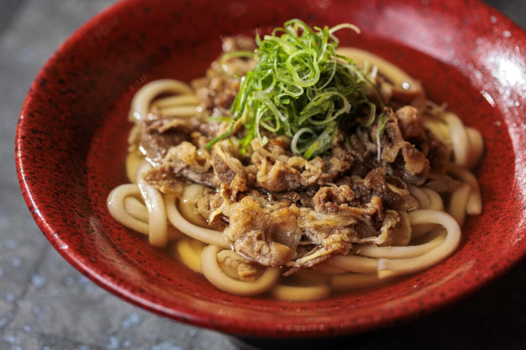 赤いお皿に盛り付けされた肉うどん