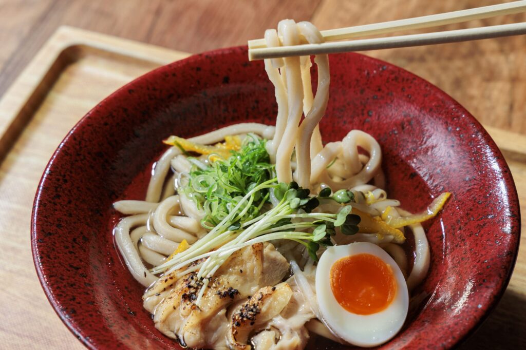 鶏肉やゆで卵や貝割れ大根が盛り付けられたうどん